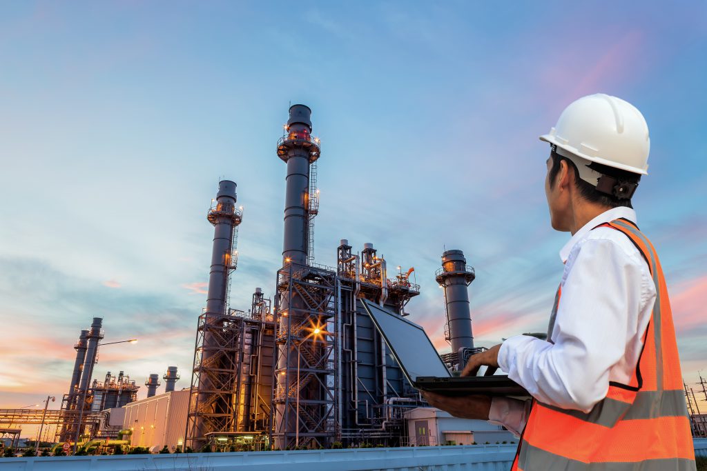 Engineering is use notebook check and standing in front of oil refinery building structure in heavy petrochemical industry