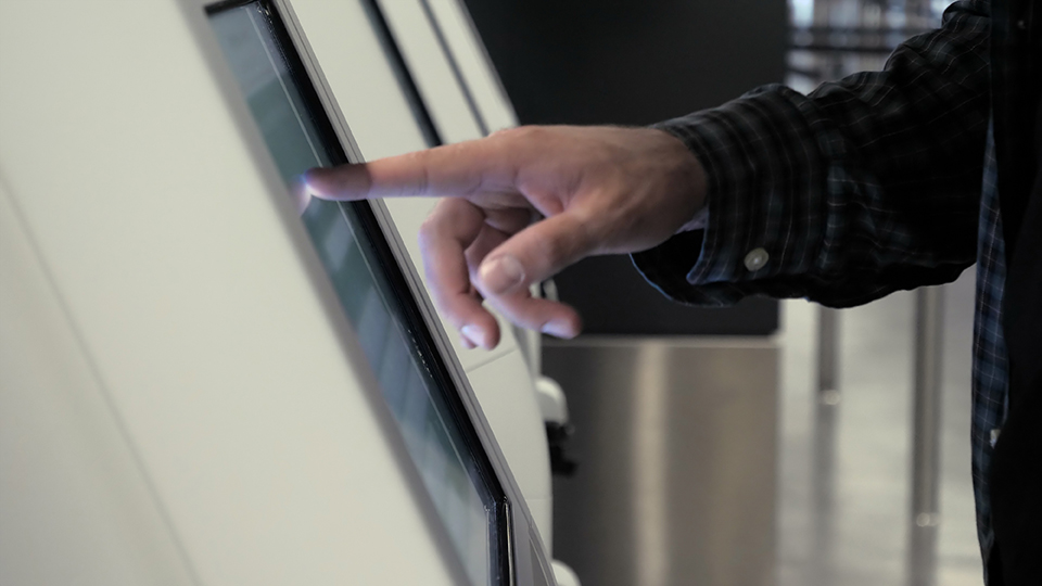 Check-in machine at the airport. Man hand typing something - About Us - Gemstone Logistics